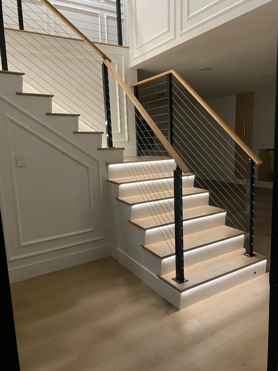 Interior staircase with modern cable railing and wood top rail